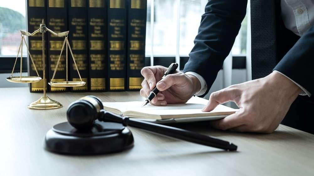 Counselor lawyer or notary working on a documents and report of Counselor lawyer or notary working on a documents and report of the important case and wooden gavel, brass scale on table in courtroom.