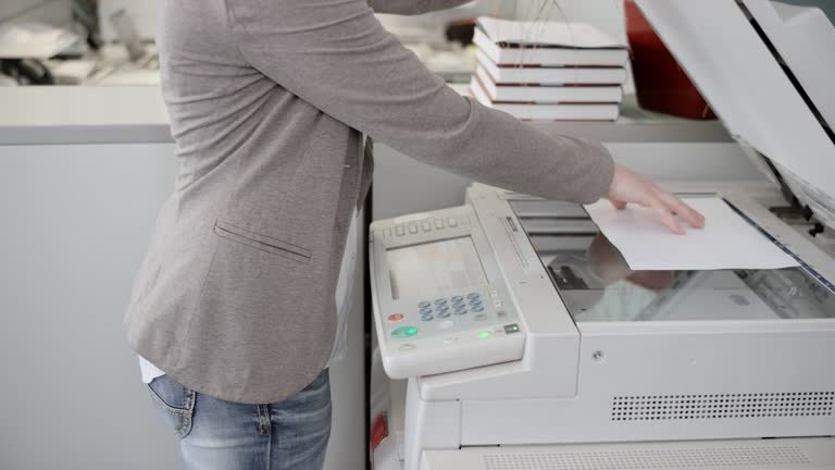 istockphoto-639680570-640x640 Medium locked down shot of a woman stepping to the copying machine in the office and placing a sheet of paper in it. Shot in Slovenia.